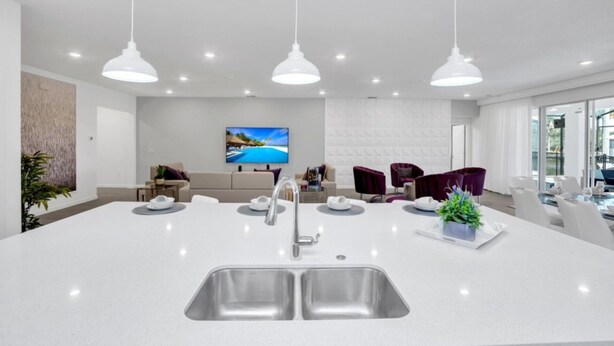 A modern kitchen with a central island, a built-in sink, and pendant lighting. - Luxury Contemporary Style Mansion on Veranda Palms Resort Orlando Mansion 5545 (Kissimmee)