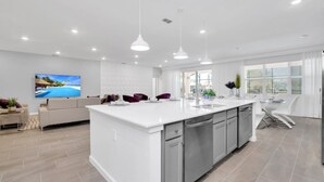 A modern kitchen with a large island, white cabinetry, and stainless steel appliances. - Luxury Contemporary Style Mansion on Veranda Palms Resort Orlando Mansion 5545 (Kissimmee)