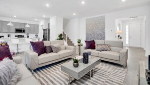 A modern living room with a sofa, coffee table, and a striped rug. - Luxury Contemporary Style Mansion on Veranda Palms Resort Orlando Mansion 5545 (Kissimmee)