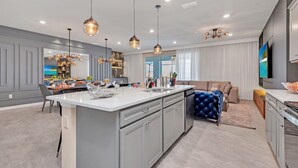 A modern kitchen with a central island, pendant lighting, and a large dining table. - You Have Found the Ultimate Luxury 10 Bedroom Mansion on Windsor Island Resort, Orlando Mansion 5531 (Kissimmee)