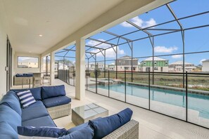Ein geräumiger Balkon mit Pool, Sitzgelegenheit im Freien und Blick auf die umliegenden Gebäude.