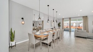 A modern dining area with a long table, multiple chairs, pendant lighting, and a view of the outdoor balcony. - Your Beautiful 5 Star Villa Minutes From Disney on the Prestigious Windsor Island Resort, Orlando Villa 5566 (Kissimmee)