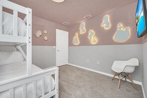 A child's bedroom with bunk beds, a white chair, and wall art. - Your Beautiful 5 Star Villa Minutes From Disney on the Prestigious Windsor Island Resort, Orlando Villa 5566 (Kissimmee)