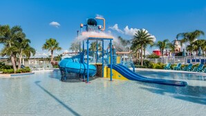A water park with a blue water slide, a water fountain, and a pool area surrounded by palm trees and lounge chairs. - 5star Villas Close to Disney, Orlando Villa 5560 (Kissimmee)