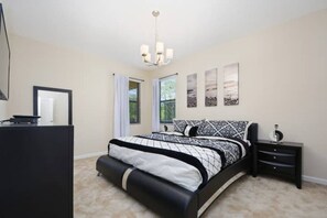 A bedroom with a bed, a bedside table, a mirror, and a window with curtains. - Amazing Villa on Veranda Palms Resort With Private Pool, Orlando Villa 5626 (Kissimmee)