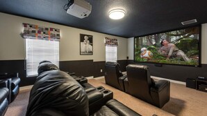 A home theater room with black leather recliners, a large flat-screen TV, and a projector. - Luxury 8 Bedroom Mansion on Champions Gate Resort, Orlando Mansion 5642 (Davenport)