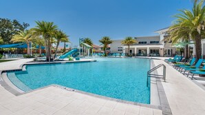 A swimming pool with a slide, surrounded by palm trees and lounge chairs. - Spacious 12 Bedroom Oasis 5649 (Kissimmee)