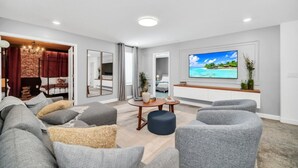 Ein modernes Wohnzimmer mit einem großen Fernseher, grauen Sofas und einer Ziegelwand.