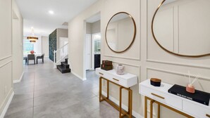 A modern hallway with a white console table, a large mirror, and a staircase leading to another room. - Ultimate Luxury Getaway With 10 Bedrooms 5659 (Kissimmee)