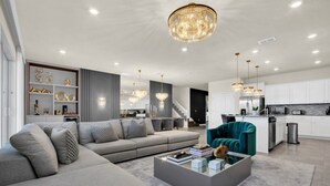 A modern living room with a grey sofa, a teal armchair, and a coffee table. - Fantastic Mansion on Windsor Island Resort, Orlando Mansion 5660 (Davenport)