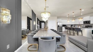 A modern kitchen with a central island, bar seating, and a chandelier. - Fantastic Mansion on Windsor Island Resort, Orlando Mansion 5660 (Davenport)