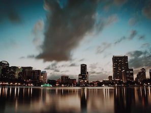 A nighttime cityscape with high-rise buildings reflected in calm water. - Luxury Mansion on Windsor Island Resort, Orlando Mansion 5658 (Kissimmee)