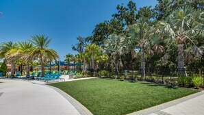 A pool area with green artificial turf, palm trees, and blue lounge chairs. - Exclusive 5 Star Mansion on Veranda Palms Resort, Orlando Mansion 5670 (Kissimmee)