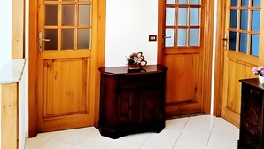 Una stanza d'angolo con porte in legno, un piccolo tavolo di legno e un pavimento piastrellato.