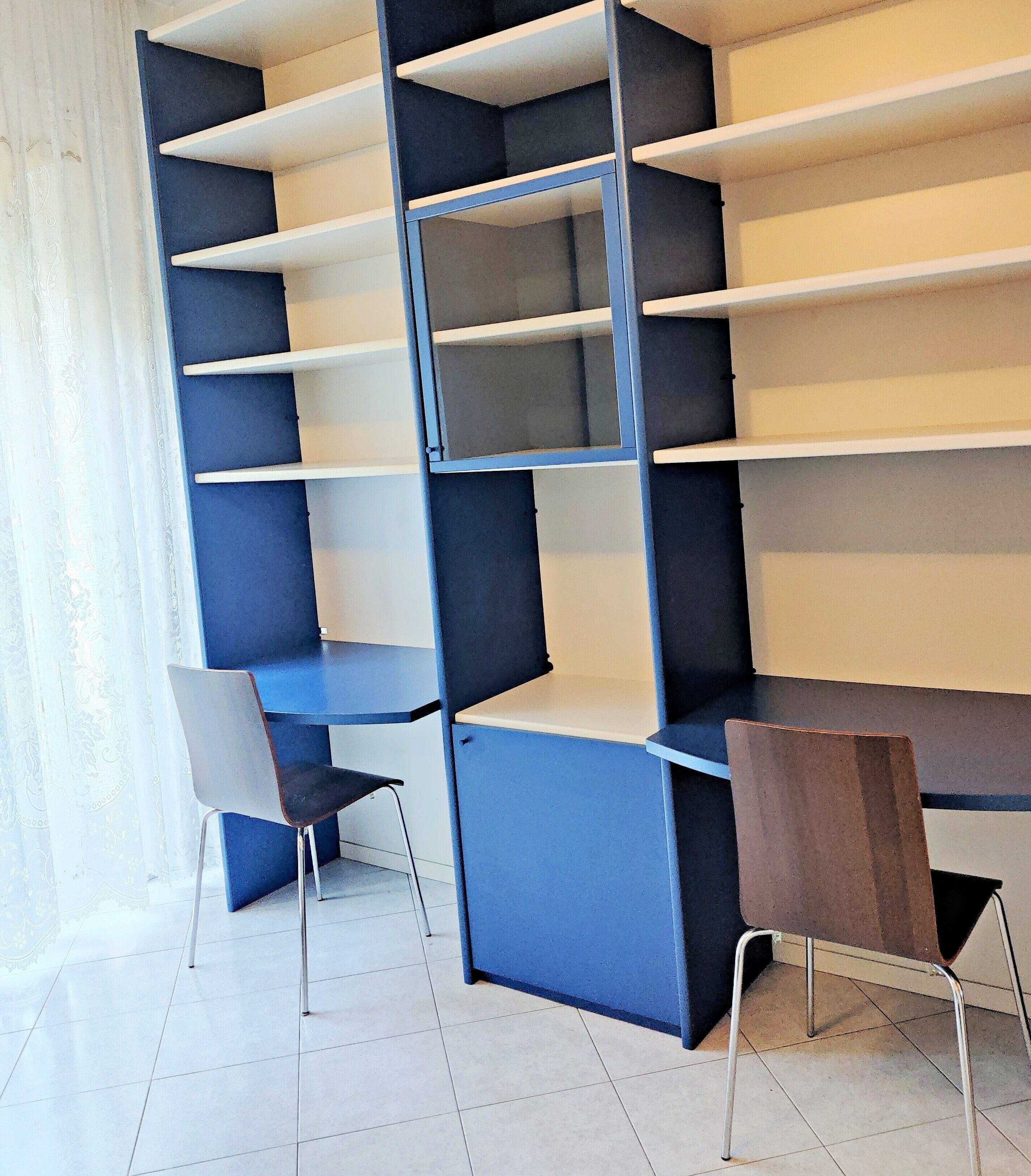 A room with a blue and white shelving unit, two chairs, and a brown table.
