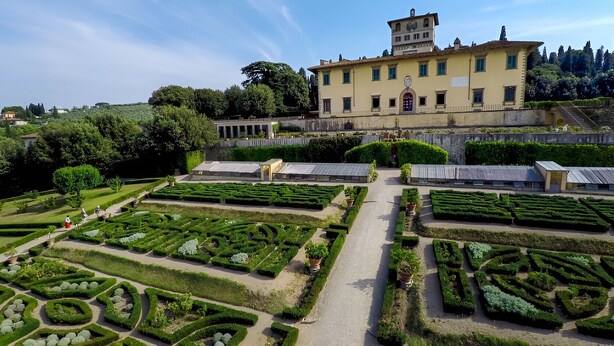Un giardino formale con motivi geometrici e un grande edificio sullo sfondo.
