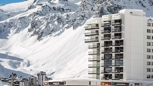 Un hotel con diversi piani, balconi e vista sulle montagne innevate.