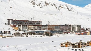 Una montagna innevata con una stazione sciistica, che comprende edifici a più piani e impianti di risalita.