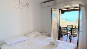 Un dormitorio con cama, un balcón con mesa y sillas, y un cartel en la pared que dice 'Love'.