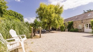 A gravel courtyard with a white chair, a stone building, and a tree.