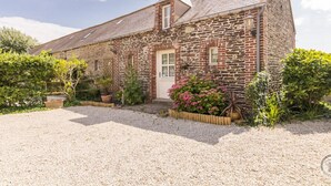 A stone building with a gravel driveway and potted plants.