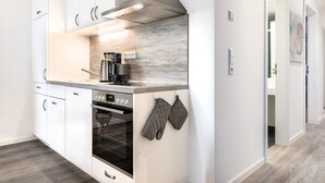 A modern kitchen with white cabinetry, a built-in oven, and a coffee maker. - Sehr Schönes Ferienapartment mit Meerblick an der Ostsee - nur 25 Meter zum Stra (Großenbrode)