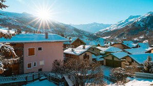 A snow-covered village with traditional buildings and a mountain backdrop. - Family chalet in the center of St Marcel with terrace for 6. (Saint-Martin-de-Belleville)