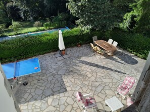 A patio with a ping pong table, a wooden table with chairs, and a lounge chair. - Creuse, Large character house in quiet area with terrace, swim. pool and garden (Auzances)