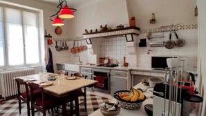 Une cuisine avec un carrelage à motifs, une table en bois dressée pour le repas, ainsi que divers ustensiles et appareils de cuisine.