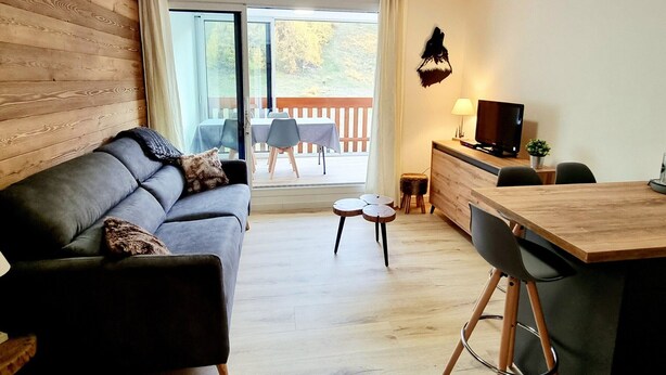 A modern living room with a sofa, a dining table, and a TV. - Renovated Studio 4 pers. at ski slopes with parking (La Joue du Loup)