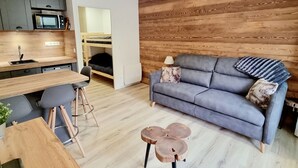 A compact living space with a kitchenette, a sofa, a dining area, and a bunk bed. - Renovated Studio 4 pers. at ski slopes with parking (La Joue du Loup)
