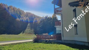 A building with a balcony, surrounded by a forested landscape and a clear sky. - Renovated Studio 4 pers. at ski slopes with parking (La Joue du Loup)