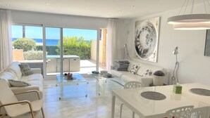 Ein modernes Wohnzimmer mit Glastür, die auf einen Balkon mit Meerblick führt.