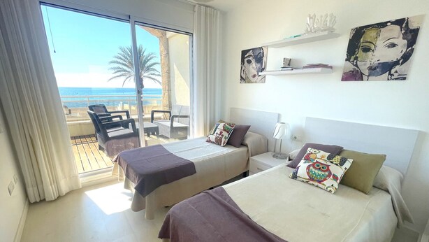 Ein Hotelzimmer mit zwei Betten, einem Balkon mit Meerblick und Kunstwerken an den Wänden.