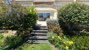 Ein Gebäude mit einem steinernen Bogen, einer Treppe, die zu einer Tür führt, und einem Garten mit verschiedenen Pflanzen und Blumen.
