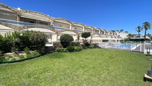 Ein Hotel mit Pool, Sitzgelegenheiten im Freien und einem gepflegten Garten.
