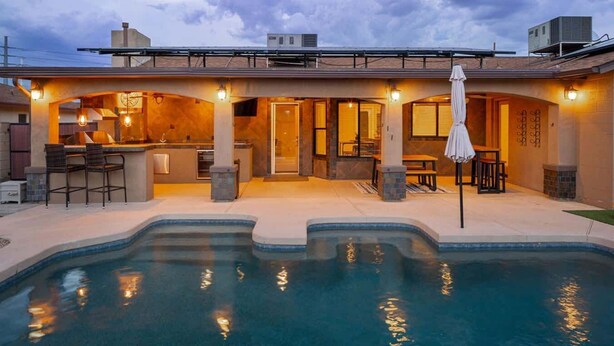 Ein modernes Haus mit Swimmingpool, Außendusche und Terrassenmöbeln.