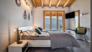 Un dormitorio moderno con cama, lámpara de noche y televisión.