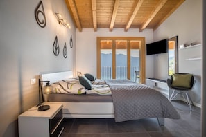 Un dormitorio moderno con cama, lámpara de noche y televisión.