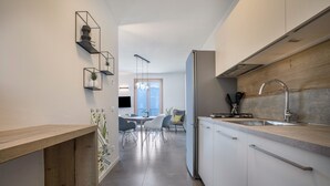 Una cocina moderna con armarios blancos, un lavamanos de acero inoxidable y una encimera de madera.