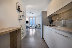 Una cocina moderna con armarios blancos, un lavamanos de acero inoxidable y una encimera de madera.