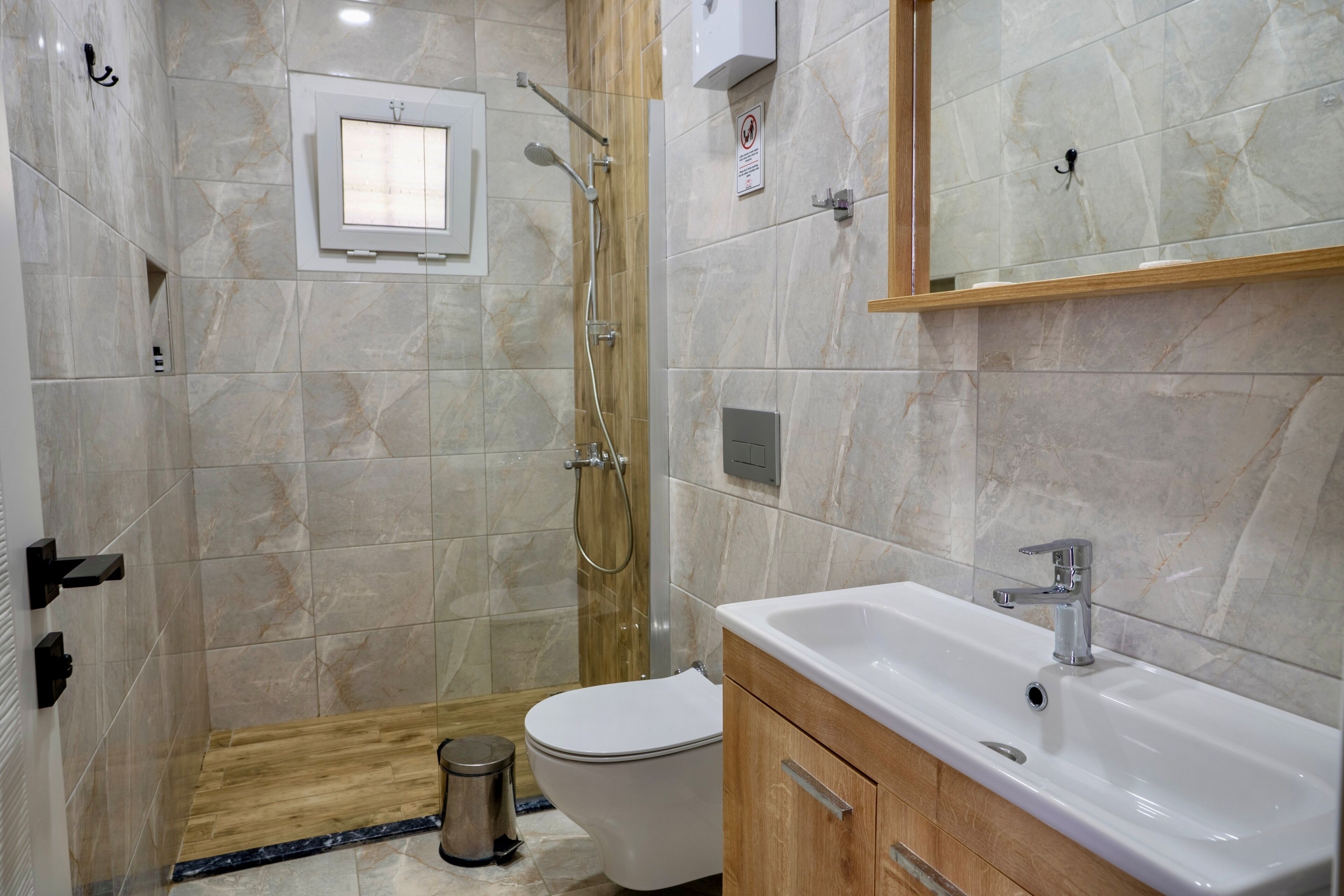 Une salle de bain avec douche, toilettes, lavabo et plancher en bois.
