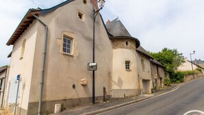A building with a stone tower, a small window, and a street in front.