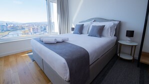 A modern hotel room with a large bed, a view of the city, and a small bedside table with a lamp. - River Walk Sarajevo (Sarajevo)