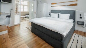 A modern bedroom with a large bed, a desk, and a TV. - The sea always works - Winterstrasse 23 (Norderney)