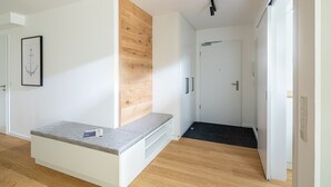 A modern hallway with a bench, a wooden accent wall, and a door leading to another room. - // VACATION APARTMENT CLOUDLESS // (Norderney)