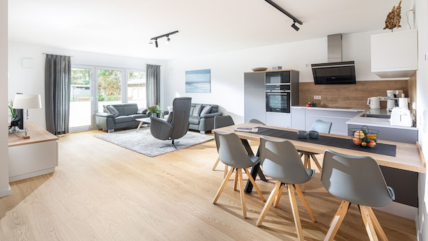 A modern kitchen with a central island, a dining area with a table and chairs, and a living area with a sofa and a coffee table. - // VACATION APARTMENT CLOUDLESS // (Norderney)