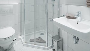A modern bathroom with a glass-enclosed shower, a white sink, and a toilet. - // REGINA MARIS - APARTMENT 1 // (Norderney)
