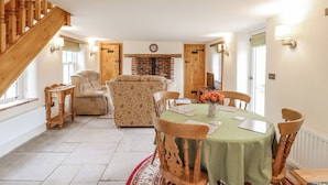 Un coin repas agrémenté d’un escalier en bois, d’une cheminée et d’une table à manger dressée pour quatre personnes.