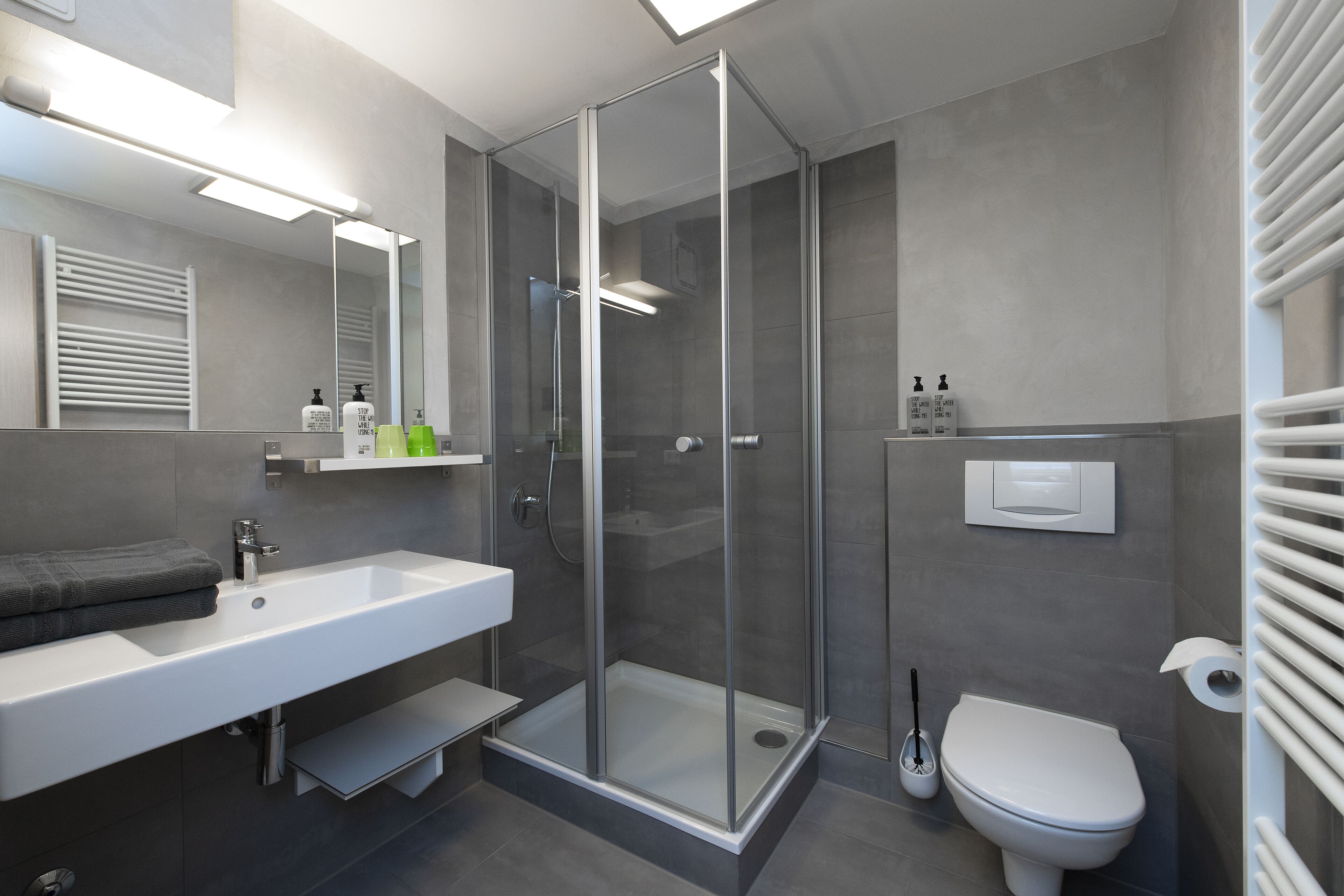 Ein modernes Badezimmer mit einer Duschkabine aus Glas, einem weißen Waschbecken und einer Toilette.
